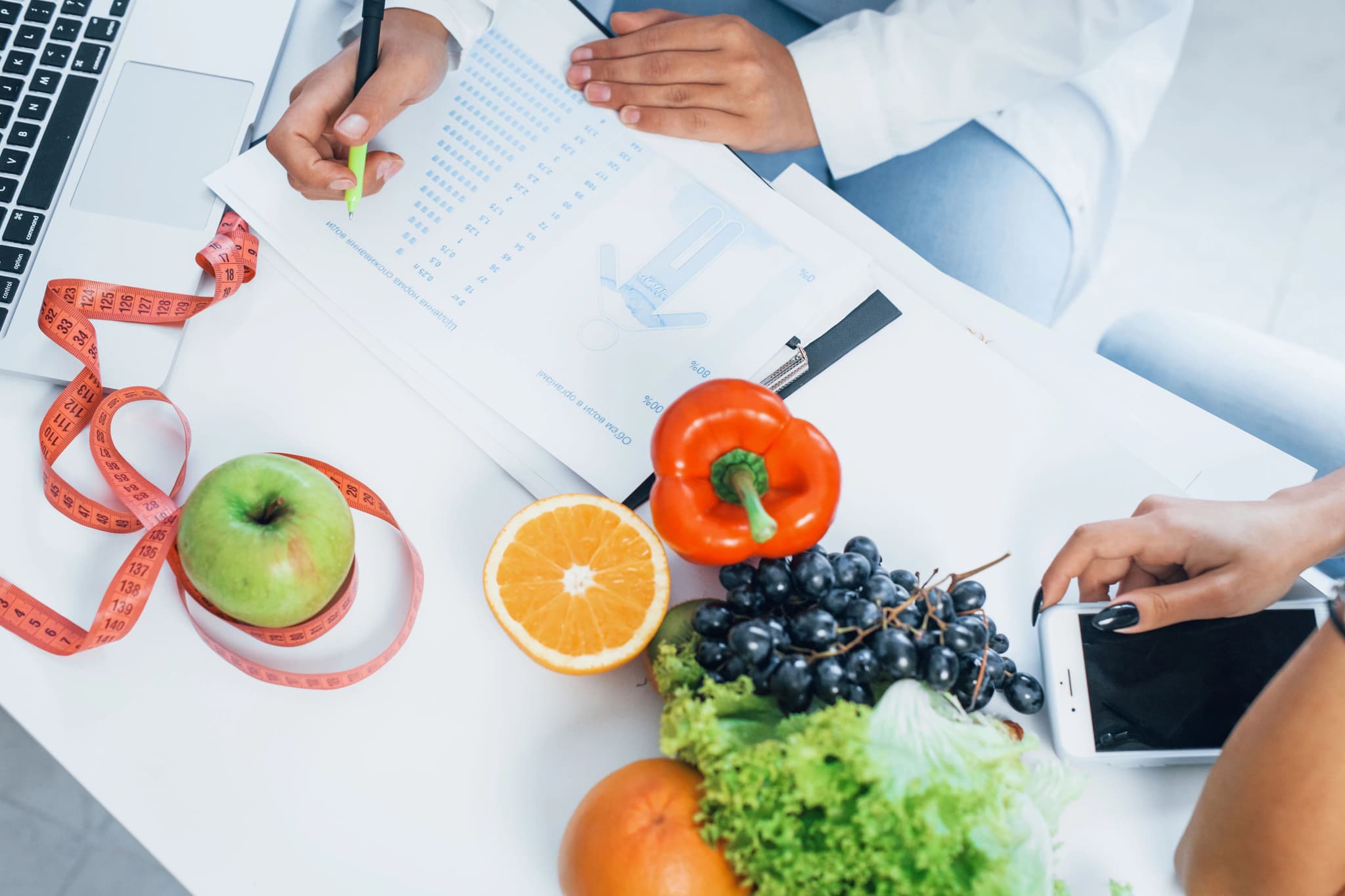 Nutritionist showing healthy eating habits with fresh vegetables and fruits - professional diet consultation